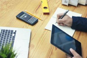 A complexidade que envolve a elaboração de captação de quantitativos e orçamentação de custos dos projetos é um dos grandes desafios do setor construtivo. A maior expectativa é por exatidão nos números, com previsibilidade e gerenciamento dos recursos. Com o BIM, a dimensão 5D entra em cena para dar mais assertividade e confiança para esse processo. Essa é uma das etapas que fazem parte do processo do Building Information Modeling, que vem remodelando a interação entre os profissionais envolvidos em um projeto, até mesmo no quesito de quantificação de mão de obra e insumos. Nas mais variadas etapas do ciclo de vida da obra, o BIM apresenta novas perspectivas de ganho, que geram resultados transformadores para a indústria construtiva. Leia mais neste post. O que é BIM? Para definir melhor o que é BIM, pode-se dizer que é uma metodologia de trabalho colaborativa, amparada nos pilares tecnologia, processos e pessoas. Enquanto os processos vão direcionar de forma padronizada o trabalho de todos os profissionais envolvidos na cadeia, como os arquitetos, engenheiros e construtores; com a tecnologia, serão utilizadas ferramentas como softwares que vão amparar as várias etapas do ciclo de vida de um projeto construtivo, como, por exemplo, o BIM Revit. O BIM permite a criação de representações gráficas que vão ''imitar" o comportamento de uma edificação física, por meio de um modelo único tridimensional, carregado de um banco de dados, que opera com um fluxo de trabalho inteligente e compartilhado entre as variadas disciplinas. Neste modelo único, que servirá tanto para o projeto arquitetônico, como para os complementares, são transmitidos escopo do projeto, etapas e resultados. Essa modelagem tridimensional inteligente é uma das principais vantagens para a análise de interferências, pois permite antecipar problemas e soluções físicas nas diversas disciplinas da obra. Além disso, a integração das áreas vai permitir um projeto com conclusão mais rápida, melhor desempenho e rentabilidade. Nessas etapas do ciclo de vida, o BIM agrega o que foi nomeado como dimensões, conforme o ciclo de vida avança as informações vão se tornando mais ricas: BIM 3D, 4D, 5D, 6D, 7D e até 8D. O 2D não está incluído no BIM, são os desenhos baseados em linhas do CAD, porém, a interoperabilidade da metodologia, permite a importação desses dados. Dimensões do BIM Vale lembrar a que se refere cada dimensão: 3D (design), 4D (compatibilização de projetos e planejamento), 5D (análise de custos), 6D (Manutenção Predial), 7D (Sustentabilidade), 8D (Segurança e Prevenção de Acidentes). Um ponto interessante a ser esclarecido é que nem sempre essas áreas das dimensões são padronizadas no mundo. Em muitos casos, o foco das dimensões 6D e 7D são alterados. Essa distribuição citada acima, está de acordo com uma padronização fornecida pela Autodesk há algum tempo. A primeira dimensão BIM é a 3D, que envolve o processo de design do modelo, com adição de informações gráficas e não gráficas de cada um de seus elementos. Já na dimensão 4D, o fator tempo é agregado. Com os dados vinculados à representação gráfica do modelo fica mais fácil entender as informações do projeto e planejar como a construção irá se desenvolver. Nesta fase de planejamento do projeto, são incluídas informações como tempos de instalação e construção, espera para a conclusão de fases na execução, sequência de instalação de componentes, ou seja, todo um cronograma é elaborado em função das informações do modelo 3D. Com as informações de sequenciamento, é possível garantir a viabilidade dos esquemas da construção desde o início do projeto. As dimensões 4D e 5D BIM estão bastante relacionadas. A 4D, relacionada à compatibilização e planejamento, é uma etapa anterior à análise de custos, porém, muito importante para a orçamentação correta. Orçamento 5D BIM: exatidão e segurança Todas as obras envolvem uma grande complexidade na captação de custos, é preciso somar todos os elementos para uma análise detalhada e profunda. Além de saber os custos com aquisição de materiais, também há custos de mão de obra, energia, água, transporte e diversos outros serviços necessários à conclusão do projeto. Porém, antes do BIM, nem sempre era possível fazer uma orçamentação correta para que a obra fosse sustentável financeiramente. Com essa extração de dados de forma manual, muitos erros podiam gerar estouros de orçamentos e até problemas para o cronograma. A extração de quantitativos exata é um dos grandes benefícios permitidos à dimensão de análise de custos. Esse resultado é possível a partir da captação das informações extraídas dos componentes do modelo 3D e inclusive as plantas técnicas derivadas dele. Esse modelo que traz informações detalhadas permite que os profissionais de orçamentação baseiem seus cálculos em componentes visíveis, que estão mais óbvios no modelo 3D, e até para elementos não visíveis, como os serviços. Por isso, é muito importante que as informações incluídas no modelo pelos profissionais envolvidos, até mesmo por profissionais como os topógrafos, sejam muito precisas na fase de design. A partir dessas informações, é possível criar um plano de custos que também vai amparar o cronograma. Dentro dessa orçamentação podem estar incluídos custos de mão de obra e insumos (como aquisição de materiais e componentes), custos de funcionamento do canteiro de obras e muitos outros. Com o 5D BIM, os profissionais da cadeia construtiva e clientes conseguem entender, analisar e até registrar o impacto das mudanças no custo dos projetos, que vai permitir uma gestão financeira inteligente. Benefícios de adotar o BIM 5D Há diversas vantagens em adotar o BIM 5D na orçamentação dos projetos, entre essas, a tomada mais rápida de decisões, devido ao trabalho colaborativo, que é um dos fortes do BIM. Esse processo já evita diversos erros que já foram tão comuns na indústria construtiva, como materiais comprados a mais ou a menos, falta de profissionais especializados e muitos outros aspectos que já travaram e provocaram prejuízos em muitas obras. Vamos conhecer mais algumas: 1 – Capacidade de visualização dos custos Com os dados fornecidos no modelo 3D é possível garantir aos orçamentistas uma facilidade muito maior para visualizar os custos. 2 – Precisão de custos Com as informações extraídas do modelo 3D, é também possível garantir uma identificação de elementos e quantificação exata. Esse fator também vai favorecer que o cronograma seja desenvolvido em conjunto com a análise desses custos. 3 – Notificações em tempo real As mudanças de componentes ou design podem impactar muito a orçamentação de um projeto. Porém, esse planejamento da dimensão 4D associada à dimensão 5D vai permitir que as alterações comunicadas em tempo real também promovam mudanças na orçamentação, mesmo antes do início da obra. Quando ocorre uma alteração no projeto, são geradas notificações e uma nova contagem de componentes é realizada. 4 – O levantamento de quantitativos ocorre a cada etapa Em todas as obras, a cada etapa é necessário um levantamento de quantitativos. Com o BIM 5D, o processo é automatizado, evitando desperdícios de materiais ou até mesmo a falta em uma determinada etapa. Em cada estágio, essas quantificações são atualizadas nos nos sistemas anexados ao projeto. 5 – Aquisição de materiais mais rápida Com o uso do BIM 5D, o processo de aquisição de materiais é bem mais rápido e ocorre na medida real da necessidade da obra, de acordo com as informações do modelo. Assim, os empreiteiros podem acessar os levantamentos e listas de materiais e agilizar a aquisição do que for preciso em certo estágio. 6 – Economia de custos O BIM 5D vai proporcionar também uma grande economia de recursos humanos e custos, devido à rapidez nos processos de informações dos custos, além de um maior controle e monitoramento sobre esses dados. 5D software BIM Para obter todos os benefícios da orçamentação com a metodologia, é possível contar com o suporte de um software 5D BIM. Esses softwares integrados ao BIM vão permitir uma estruturação de planilha de orçamento de obra, onde podem constar todos os materiais e serviços. Entre esses softwares compatíveis com o BIM está o Orçafascio, que reúne diversas ferramentas para criação de um orçamento realista e assertivo e permite a realização de um orçamento 8 vezes mais rápido do que um processo tradicional. Além disso, as principais instituições privadas e públicas também já utilizam o software, que tem grande popularidade entre arquitetos, engenheiros e construtores. Conclusão Para profissionais do setor que querem dominar a dimensão BIM 5D e ensinar como fazer um orçamento de obra, uma dica é investir em uma qualificação neste estágio da obra, a partir de um curso. O Grupo AJ BIM oferece o curso Orçamento de Obras com BIM para capacitar profissionais no uso das ferramentas da metodologia. Com essa qualificação, o aluno aprende a elaborar orçamentos muito precisos e cronograma físico-financeiro realista.